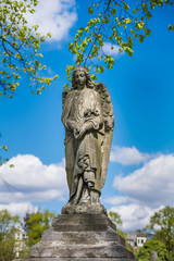 Angel statue in a cemetery  with clouds and blue sky