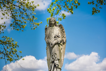 Angel statue in a cemetery  with clouds and blue sky