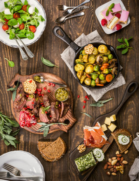 Flat lay of delicious dinner table with roasted meat steak, appetizers and desserts. Top view. Healthy food concept.