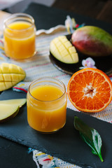 Fresh mango and orange detox drink over black slate.