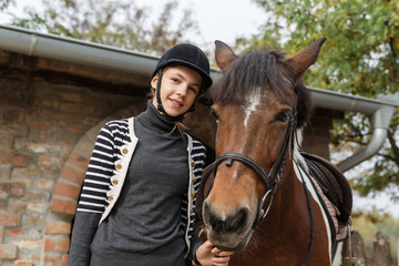 Fototapeta premium Teenage girl with her horse in front of a stable