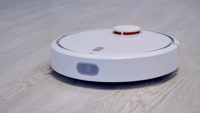 A robotic vacuum cleaner works on a laminate flooring. 