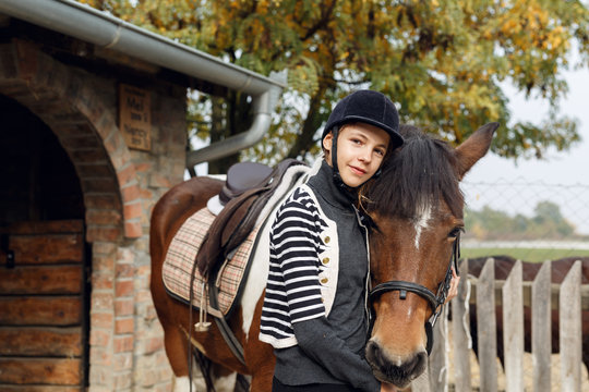 Preparing for training. Teenage girl with her horse in front of a stable