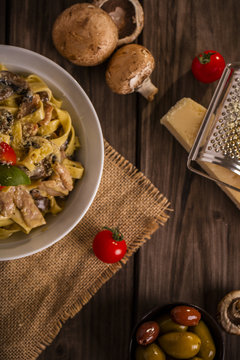 chicken and mushroom tagliatelle shot on wood boards top view close-up with a copper pot loose mushrooms parmesan block grater basil portrait