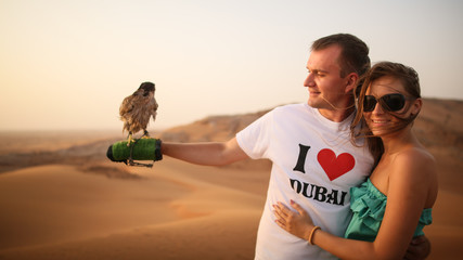 Girl and the guy keep on hand eagle. Desert in Abu Dhabi, United Arab Emirates.