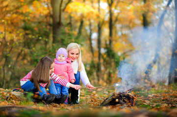 happy family outdoors in a beautiful park, fry marshmallows on fire and eat.