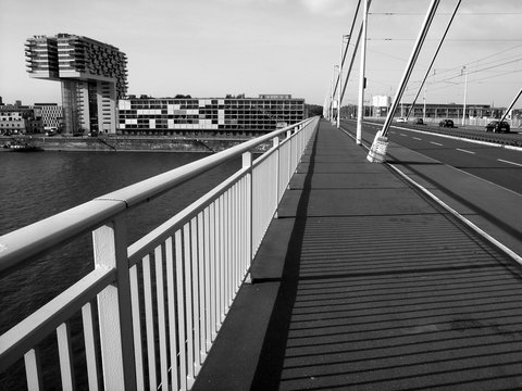 Fototapeta Spaziergang über die Severinsbrücke Richtung Rheinauhafen mit Kranhaus an einem sonnigen Sonntag in Köln am Rhein in Nordrhein-Westfale , fotografiert in neorealistischem Schwarzweiß