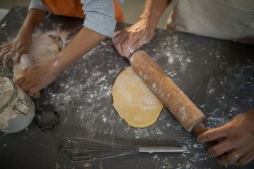 Grandmother and granddaughter flattening dough