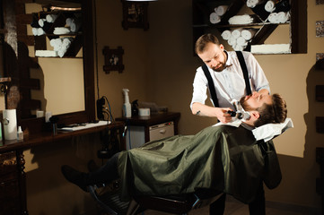 Master cuts hair and beard of men in the barbershop