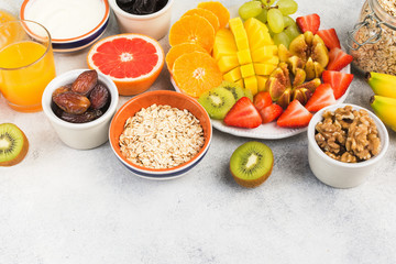 Top view of healthy breakfast with oats, variety of fruits, strawberries, mango, grapes, served on the white table, selective focus