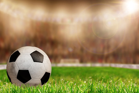 Soccer Ball on Field With Brightly Lit Stadium Background and Copy Space