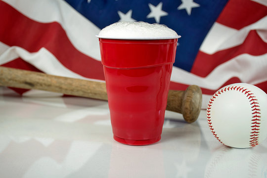 American flag with beer in red cup and wooden bat with baseball