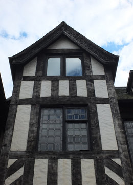 tudor type british house with black timbers and white plaster walls and leaded windows
