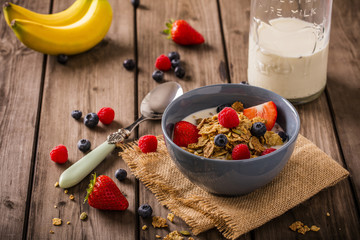 breakfast cereal shoot on wood boards angled view with raspberries blueberries bananas strawberries...