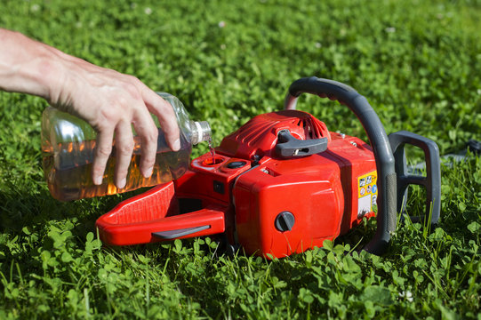 Handyman replenishes the oil in chainsaw for chain maintenance