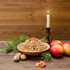Obraz premium Plate with traditional Christmas treat Slavs on Christmas Eve. Spruce branch, apples and candle on a wooden background