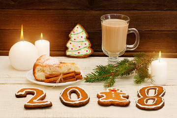 Christmas dinner and gingerbread, spruce branch, candle, cappuccino and apple pie on a wooden table