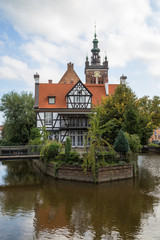 Miller's House (Dom Mlynarza) at the Mill Island on Raduni Canal in Gdansk's Old Town in Poland. It's the old headquarters of the Millers guild. St. Cathrine's Church is in the background.