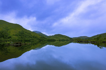 Fototapeta premium Beautiful and serene landscape of a lake and mountains in the Highlands of Scotland, United Kingdom; Concept for travel in Scotland