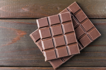 Bitter, dark chocolate bar on wooden planks background, top view