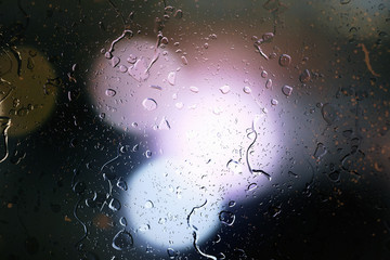 Raindrops on a car window with beautifully blurred background of street traffic lights