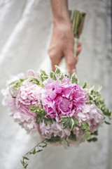 hand of the bride with a beautiful wedding bouquet of peonies