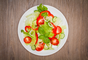 fresh vegetarian salad in a white plate on the wooden table