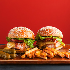 delicious homemade burgers with a juicy veal cutlet on a wooden table, against a red wall background