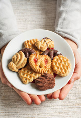 Child's hands hold Christmas festive homemade cookies on a plate