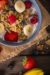 breakfast cereal shot on wood boards top view close-up with raspberries blueberries bananas strawberries portrait