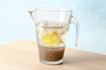 Jug of water with chia seeds and citrus slices on table