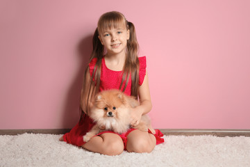 Cute girl with little dog against color wall