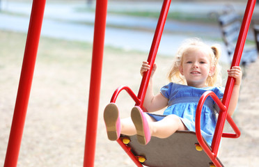 Adorable little girl on swing at playground