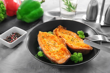 Plate with baked sweet potato on table
