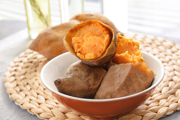 Dish with baked sweet potato on wicker mat