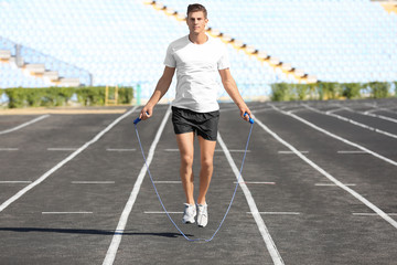 Young man skipping rope at stadium
