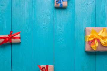 Blue wooden boards. A festive gift. Boxes tied with colored ribbons. Four boxes left, right, top, bottom
