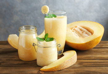 Jars and glass of fresh melon smoothie on wooden table