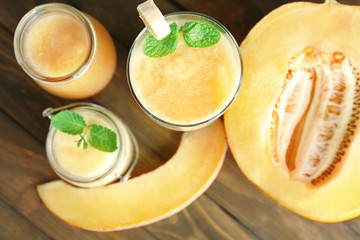 Jars and glass of fresh melon smoothie on wooden table, closeup