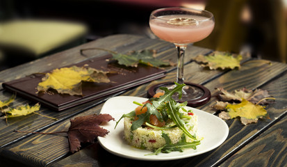 bulgur with salmon with wild rocket on top with cocktail on wooden table
