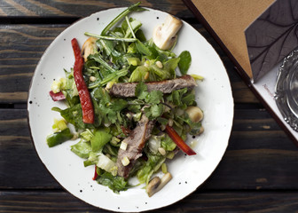 Thai salad with beef on wooden table