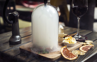 tartar beefsteak under glass bell filled with smoke on wooden table