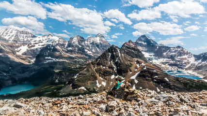 Fototapeta na wymiar hikers sitting on a cairn at the top of Odaray Highline trail overlooking Lake O'Hara and Lake McArthur