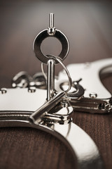 close-up shot of handcuffs and keys on the brown wooden table background
