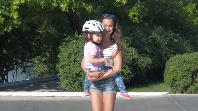 Children roll on roller skates. The child is sitting in the arms of the sister.