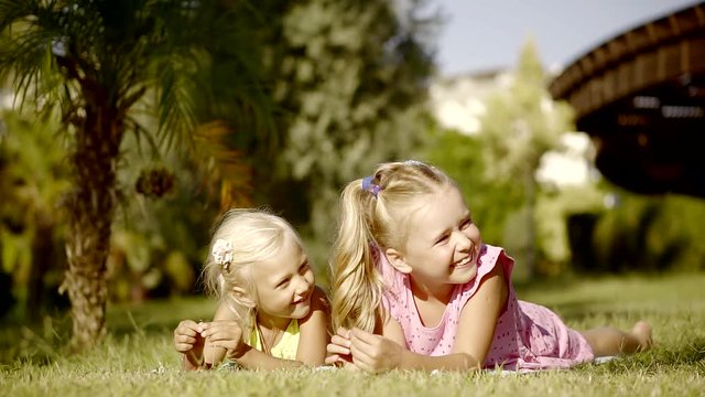Little girl lying on the grass in the park, children enjoy summer vacation and smiling looking aside