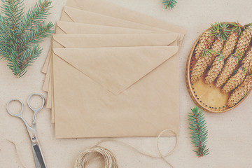 Christmas gifts and letters handmade, and everything necessary for them. Envelopes of Kraft paper, scissors, spruce cones and jute cord. The view from the top. The concept of simplicity