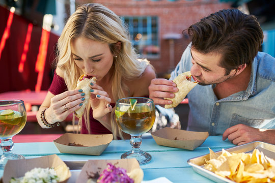 romantic couple eating street tacos at outdoor mexican restaurant