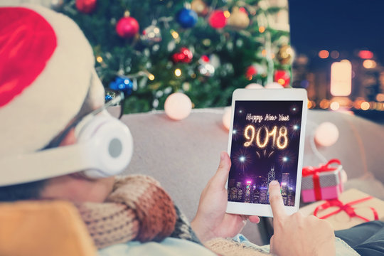 Man celebrate new year 2018 fireworks with tablet,Happy people lay on sofa and countdown from home with christmas tree at night,Holiday celebration with technology.