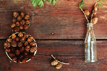 Christmas background on old wooden boards with decorative element in the shape of a figure eight, antique bottle and cones of larch